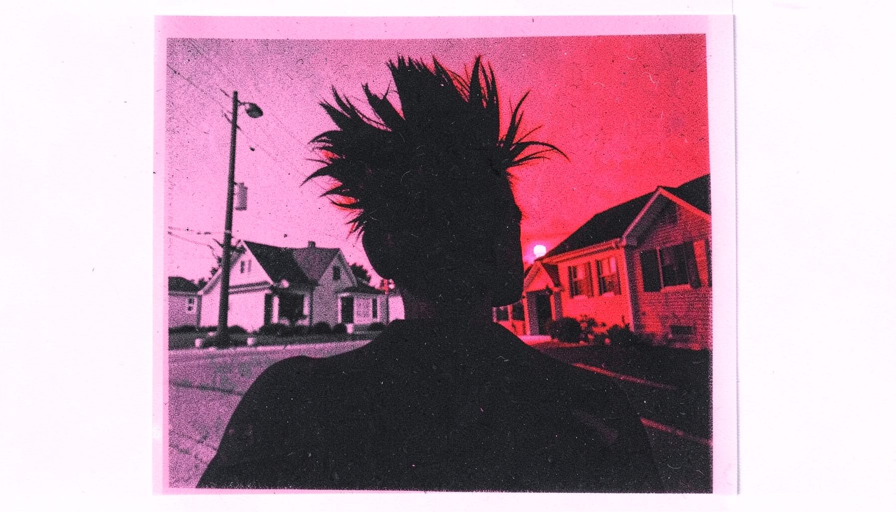A two-ink risograph print in bubblegum pink and charcoal black, depicting a gothic silhouette with teased hair against a neon-lit suburban backdrop